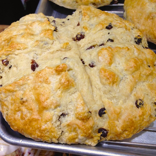A round Irish Soda Bread, golden-brown, with the traditional cross cut into the top crust.